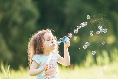 happy children playing with soap bubbles on a summer nature. bubbles in the sunset. focus on the child, or soap bubbles