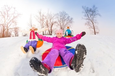 girl and her friends sliding down hill on tubes