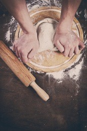 making dough by mens hands on wooden table background