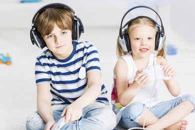 cute boy and girl playing game in wireless headphones