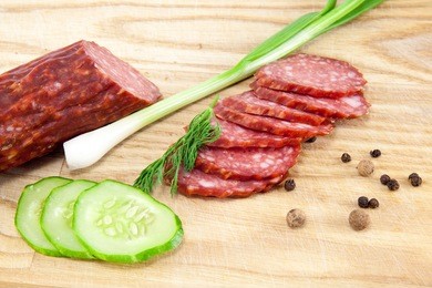 slice of salami sausages on wooden board isolated