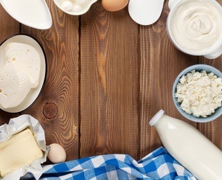 dairy products on wooden table. sour cream, milk, cheese, eggs, yogurt and butter. top view with copy space