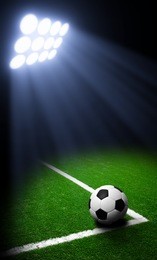 soccer ball on green stadium, arena in night illuminated bright spotlights
