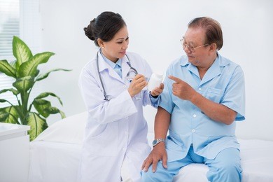 female doctor giving pills to her senior patient