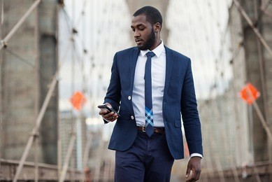 young businessman using mobile phone on brooklyn bridge. new york city.