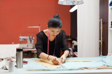 asian woman tailor fashion clothes dress designer working with fabric on table