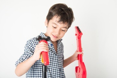 little boy playing guitar and sing with microphone