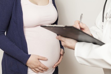 doctor with clipboard in front of pregnant