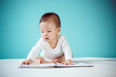 asian baby writing in a book and sitting on the bed in the blue room, baby healthy and preschool concept