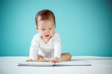 little girl writing in a book and sitting on the bed in the blue bedroom, baby healthy and preschool concept