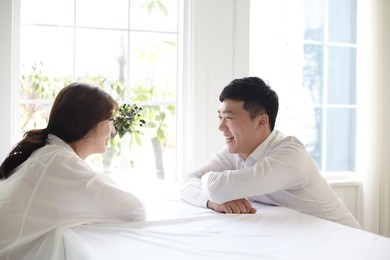 beautiful young couple having a conversation while looking at each other over a window background in a bright room
