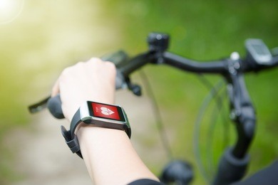  woman riding a bike with a smartwatch heart rate monitor. smart watch concept.