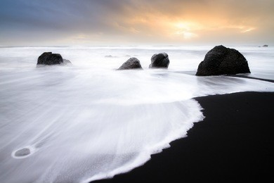 beautiful sunset view of the black sand and rough sea at the beach of vik in iceland