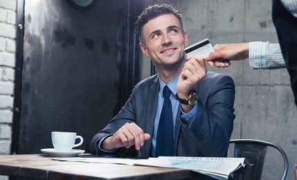 happy businessman passing his credit card to waiter in cafe