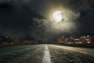 asphalt road leading into the city at night