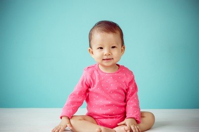 asian baby girl smiling and sitting on the bed in the blue bedroom, baby healthy and preschool concept