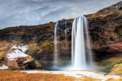beautiful view of the seljalandsfoss waterfall in iceland with ominous clouds in winter