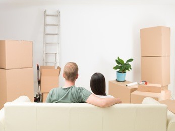 rear view of couple sitting on sofa after moving in new house