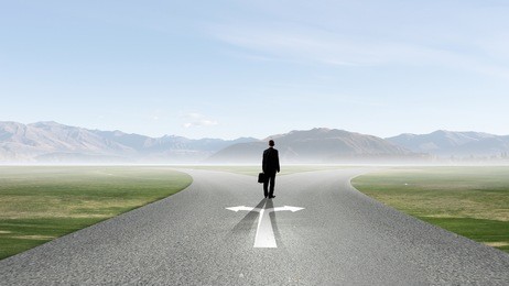 back view of businessman standing at crossroads and making choice