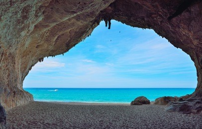 motorboat passing by a big cave in cala luna, sardinia