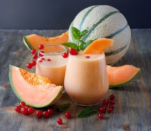 healthy smoothie vitamins drink with red currant fresh berries, mint and cantaloupe melon, shake with yogurt for breakfast on wooden rustic background, summer harvest beverage, diet concept