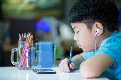 a boy using cellphone and painting on a white paper at home