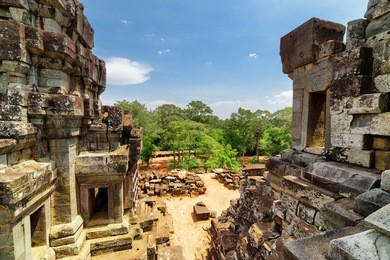 view of mysterious ruins of ancient ta keo from top of temple. amazing angkor, siem reap, cambodia. blue sky and woods in background. angkor is a popular tourist attraction.