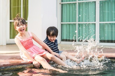 asian children splashing around in the pool