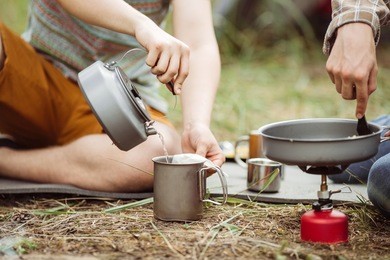 two fellow campers making tea and preparing food in the forest