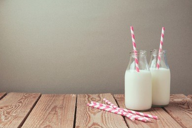 milk bottles with retro striped straws on wooden table