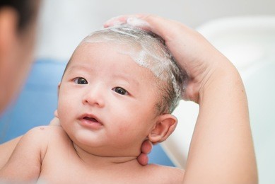 mother give a bath her newborn baby in bathroom, focus at the eye