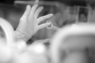 a tiny baby hand catching a doctor's little finger