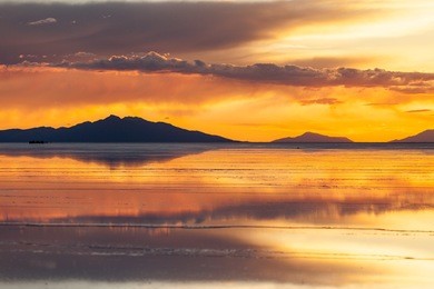 sunset in salar de uyuni. reflection of the clouds in the wet surface of salt. mountain and clouds background