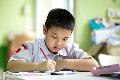 young asian boy doing his homework at home