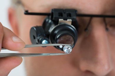 close-up of person looking at diamond with magnifying loupe