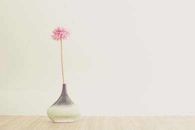 still life with jug and pink flower on the top of wooden table