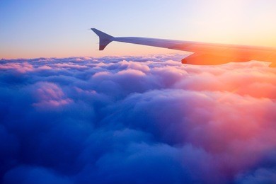 airplane wing in flight from window, sunset sky