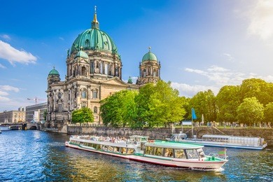 beautiful view of berliner dom (berlin cathedral) at famous museumsinsel (museum island) with excursion boat on spree river in beautiful evening light at sunset, berlin, germany