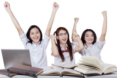 group of three excited teenage high school students expressing success and raise hands together, isolated on white background