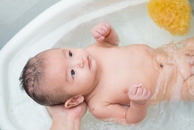mother give a bath her newborn baby in bathroom, focus at the eye