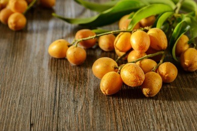 fresh wampee fruit on the wooden board