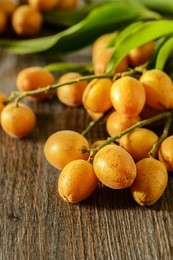 fresh wampee fruit on the wooden board