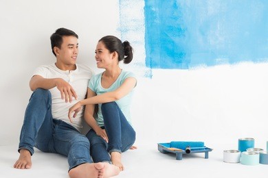 young couple resting on the floor after painting the wall