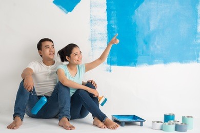 vietnamese young couple taking break from painting the wall in new apartment