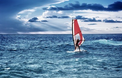 windsurfer in the sea, man on windsurf conquering the waves, enjoying extreme sport, active lifestyle, happy summer vacation
