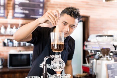 barista preparing drip coffee in asian coffee shop using professional machine parts 