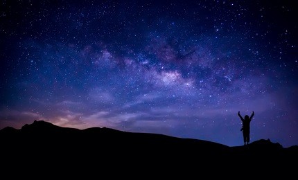 silhouette of a happy photographer adventure trekking on  mountain with real fantasy stars and milky way in the night sky. conceptual of amazing nature with great dream journey and voyage scene. 