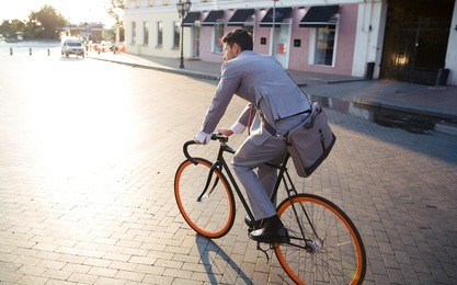businessman riding bicycle to work on urban street in morning