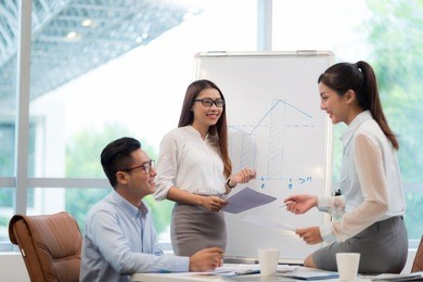 young vietnamese business team discussing chart on a whiteboard
