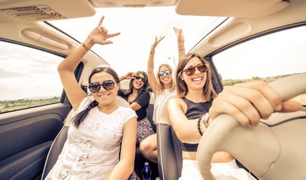 four girls driving in a convertible car and having fun 